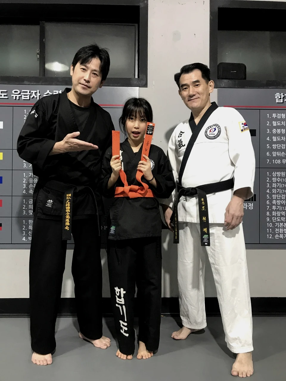 주황띠 승급을 축하받는 합기도 수련생과 지도진